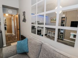 A living room with a couch and kitchen view at Estuary Escape in Porthmadog