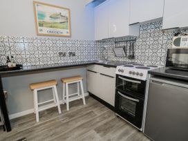 A kitchen with appliances and bar stools at Estuary Escape in Porthmadog