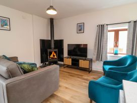 A living room with a fireplace tv sofa and two blue armchairs at Ladybird Rest in Parkham near Bideford