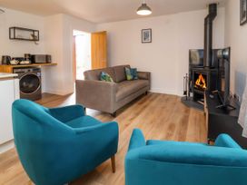 A living room with two blue armchairs a grey sofa a wood burning stove and a television at Ladybird Rest in Parkham near Bideford