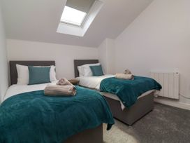 A bedroom with two single beds with teal blankets and pillows under a skylight at Ladybird Rest in Parkham near Bideford
