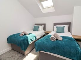 A bedroom with two single beds with teal blankets and pillows and rolled towels on the beds at Ladybird Rest in Parkham near Bideford