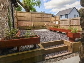 An outdoor garden area with wooden planters on a gravel ground and wooden fences surrounding at Ladybird Rest in Parkham near Bideford