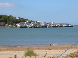 A beach with two dogs playing in the water and a coastal town in the background at Ladybird Rest in Parkham near Bideford