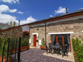 An outdoor patio with a table and chairs outside a stone building at Bumblebee Meadows in Parkham near Bideford