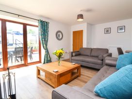 A living room with grey sofas a wooden coffee table with flowers and large glass doors at Bumblebee Meadows in Parkham near Bideford