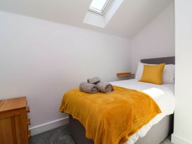 A bedroom with a bed covered in white sheets and a yellow blanket with towels on top at Bumblebee Meadows in Parkham near Bideford