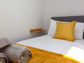 A bed with white sheets a yellow pillow and blanket and rolled grey towels on the side at Bumblebee Meadows in Parkham near Bideford