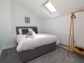 A bedroom with a double bed white bedding folded towels on the bed skylight window and a wooden clothes rack at Bumblebee Meadows Parkham near Bideford