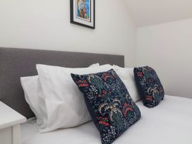 A bed with white pillows and patterned cushions and a framed picture above at Bumblebee Meadows Parkham near Bideford