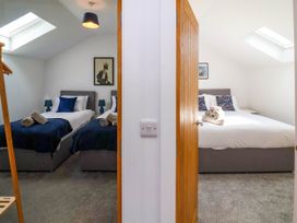 Two adjoining bedrooms each with beds, bedding, bedside tables with lamps, skylights, and towels on the beds at Bumblebee Meadows Parkham near Bideford