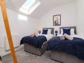 A bedroom with two single beds with blue blankets and pillows and towels on them with a skylight window at Bumblebee Meadows Parkham near Bideford