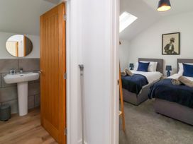 A bedroom with two single beds and a bathroom with a sink and mirror at Bumblebee Meadows in Parkham near Bideford