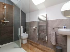 A bathroom with a shower area toilet sink towel and mirror at Bumblebee Meadows Parkham near Bideford