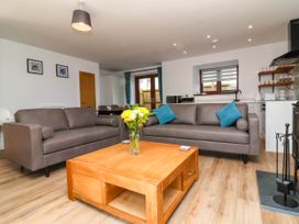 A living room with two sofas a wooden coffee table with flowers and kitchen appliances at Bumblebee Meadows in Parkham near Bideford