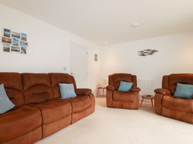 A living room with brown furniture and photographs on the wall at Blissful Ocean Breeze in Perranporth