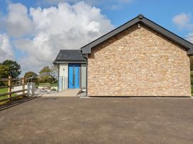 An outdoor view of a house with stone wall and blue door at Lake View Kestle Mill near Quintrell Downs