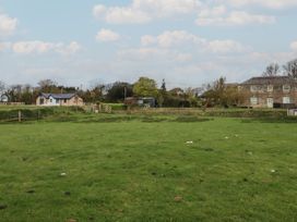 A grassy field with buildings and trees at Lake View near Kestle Mill near Quintrell Downs