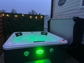 An outdoor hot tub with green lights next to a mobile home at Swan Lodge in Swannington near Coalville