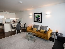 A living room with a yellow sofa, glass coffee table, dining area, and kitchen at Apartment 17 Abbey Sands in Torquay