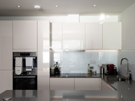 A modern kitchen with built in oven stovetop kettle coffee machine and sink at Apartment 17 Abbey Sands in Torquay