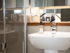 A bathroom sink with a soap dispenser and a faucet next to a shower with glass doors at Apartment 17 Abbey Sands in Torquay