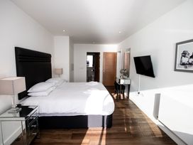 A bedroom with a bed nightstands lamps a wall-mounted television a vanity mirror and wooden doors at Apartment 17 Abbey Sands in Torquay