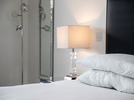 A bedroom with two pillows on a bed a bedside lamp and a mirror at Apartment 17 Abbey Sands in Torquay