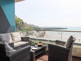 A balcony with wicker chairs and a table overlooking a beach and a pier at Apartment 17 Abbey Sands in Torquay