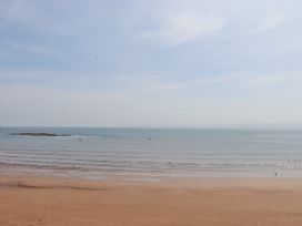 A beach with wet sand and calm sea under a partly cloudy sky at Apartment 17 Abbey Sands in Torquay