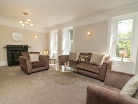 A living room with brown sofas a glass coffee table and a black fireplace at Serenity House The Retreat in Llangammarch Wells near Llanwrtyd Wells
