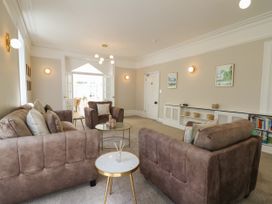 A living room with brown sofas, round coffee tables, wall lights, and paintings at Serenity House The Retreat in Llangammarch Wells near Llanwrtyd Wells