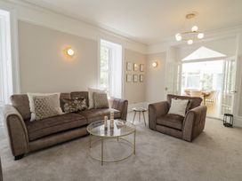 A living room with a brown sofa and armchair a glass coffee table and a side table at Serenity House The Retreat in Llangammarch Wells near Llanwrtyd Wells