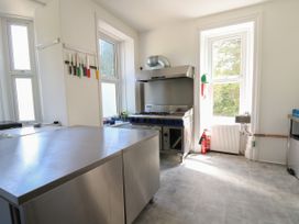 A commercial kitchen with stainless steel counters a stove knives on a magnetic strip and windows at Serenity House The Retreat in Llangammarch Wells near Llanwrtyd Wells
