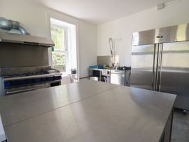 A professional kitchen with a large stainless steel worktable a gas stove a double door refrigerator a sink and kitchen equipment at Serenity House The Retreat Llangammarch Wells near Llanwrtyd Wells
