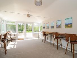 A room with high stools and a long wooden counter and wall art of brighton devon norfolk scotland wales at Serenity House The Retreat in Llangammarch Wells near Llanwrtyd Wells