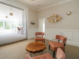 A sitting area with four chairs around a wooden coffee table in a room with beige walls at Serenity House The Retreat in Llangammarch Wells near Llanwrtyd Wells