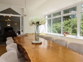 A dining room with a wooden table and white flowers in a vase at Serenity House The Retreat in Llangammarch Wells near Llanwrtyd Wells