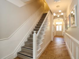 A hallway with carpeted stairs on the left wooden flooring and framed pictures on the right wall at Serenity House The Retreat in Llangammarch Wells near Llanwrtyd Wells