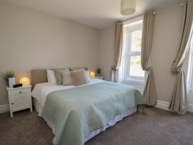 A bedroom with a bed pillows nightstands lamps and windows with curtains at Serenity House The Retreat in Llangammarch Wells near Llanwrtyd Wells