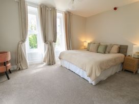A bedroom with a bed with pillows bedside tables with lamps and windows with curtains at Serenity House The Retreat in Llangammarch Wells near Llanwrtyd Wells
