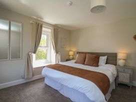 A bedroom with a bed a window with curtains two bedside tables with lamps and two mirrors on the wall at Serenity House The Retreat in Llangammarch Wells near Llanwrtyd Wells