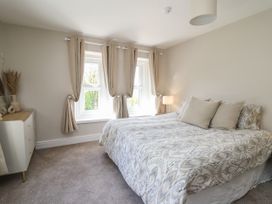 A bedroom with a bed a dresser and windows with curtains at Serenity House The Retreat Llangammarch Wells near Llanwrtyd Wells