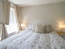 A bedroom with a bed with patterned bedding two bedside tables with lamps and beige curtains at Serenity House The Retreat in Llangammarch Wells near Llanwrtyd Wells