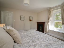 A bedroom with a bed pillows a window with curtains a fireplace and a clothes rack at Serenity House The Retreat in Llangammarch Wells near Llanwrtyd Wells