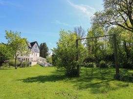 A large grassy garden with two swings and a house in the background at Serenity House The Retreat in Llangammarch Wells near Llanwrtyd Wells