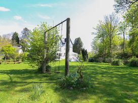A garden with swings and trees near a house at Serenity House The Retreat in Llangammarch Wells near Llanwrtyd Wells