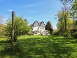 A large white house with two conservatories and a wide lawn with trees at Serenity House The Retreat in Llangammarch Wells near Llanwrtyd Wells