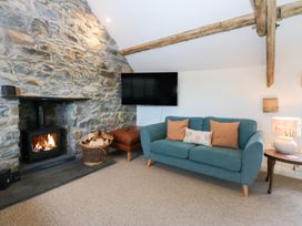 A living room with a sofa and wood-burning stove at Yr Hen Felin in Dyffryn Ardudwy