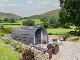 A cabin with a deck and furniture near a green landscape at Caban Tirion in Dinas Mawddwy near Dolgellau